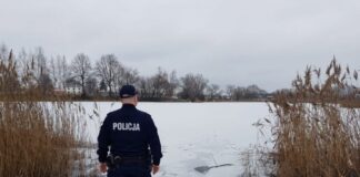 policjant przed zbiornikiem skutym lodem