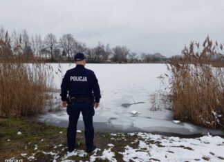 policjant przed zbiornikiem skutym lodem